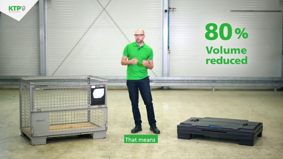 A presenter in a green shirt stands in a warehouse near a metal cage and a black flat packaging solution, highlighting an "80% Volume reduced" message.