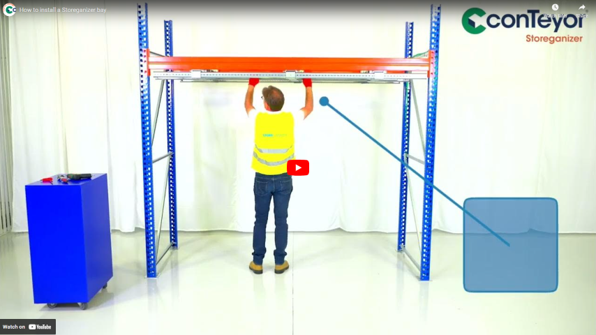 A person in a yellow vest is installing a shelving unit in a warehouse, with a video play button and a blue box in the corner.