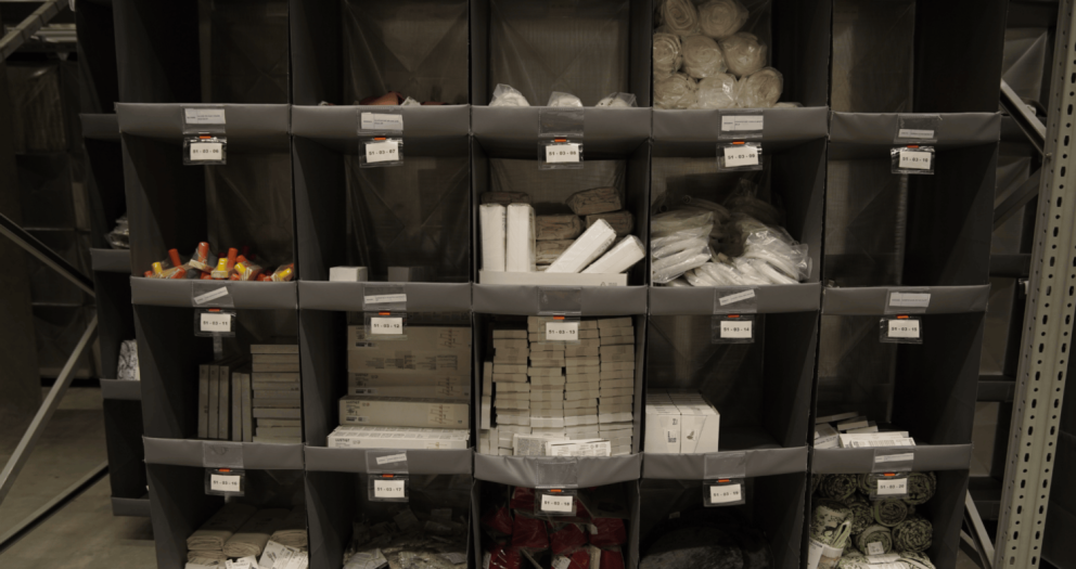 Storage shelves filled with various packaged items, labeled with identification tags.