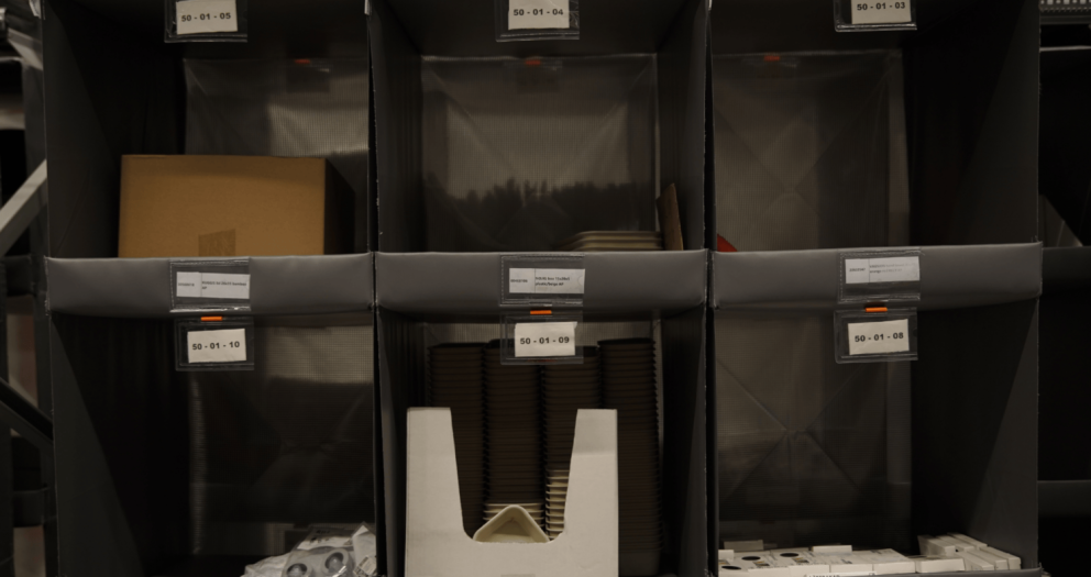 Shelves with labeled compartments displaying various items, including a cardboard box and stacks of plates.