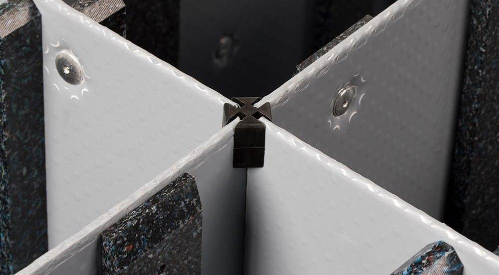 Close-up view of a black connector at the intersection of four textured panels, two white and two dark, showcasing their edges and fasteners.