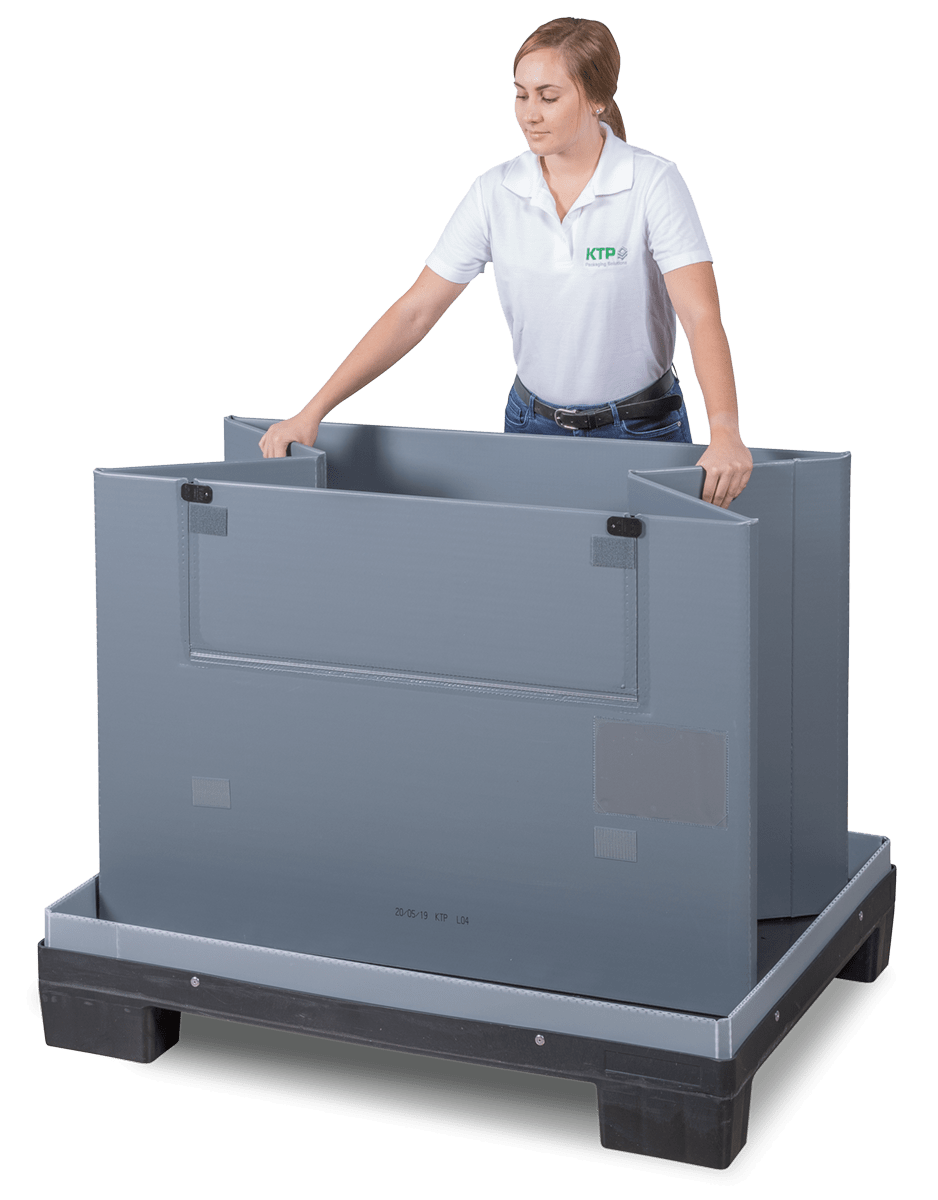 A woman in a white polo shirt stands next to a gray, stackable storage container, preparing to assemble it.