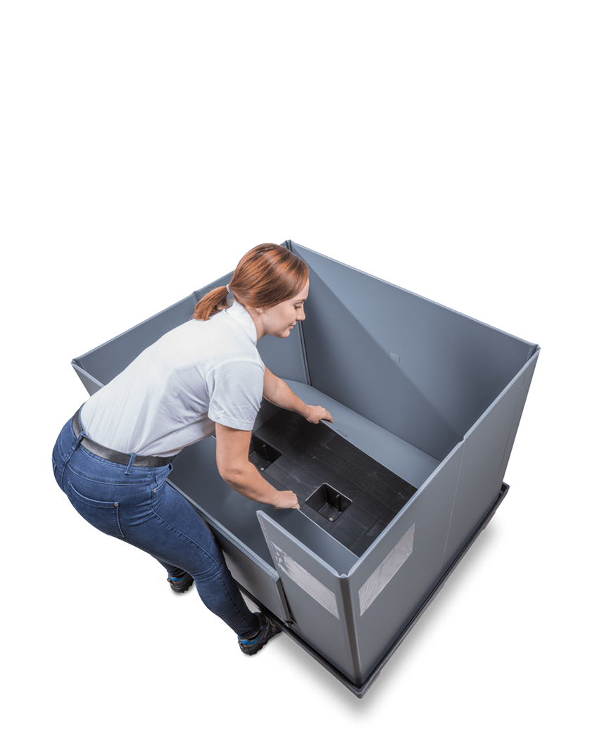 A woman assembling a large gray storage bin, focusing on the base inside the bin.