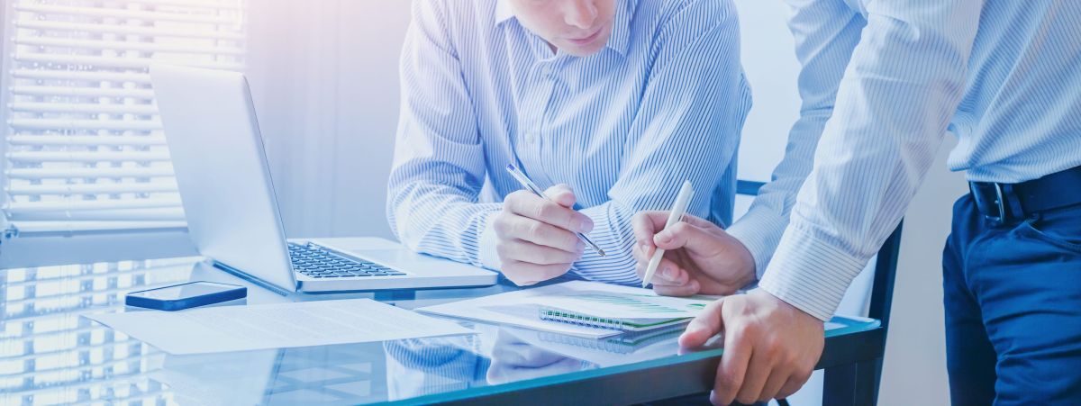 Two men with a pen in their hands pointing at a legal document