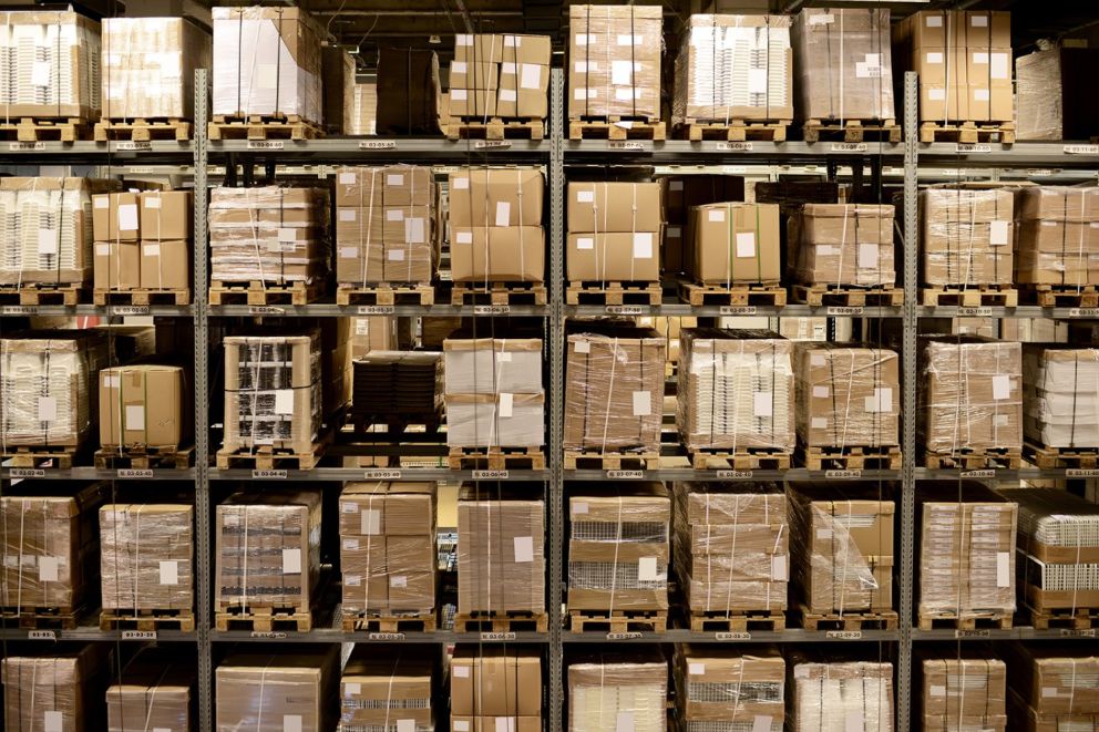 A storage warehouse filled with stacked cardboard boxes and pallets.