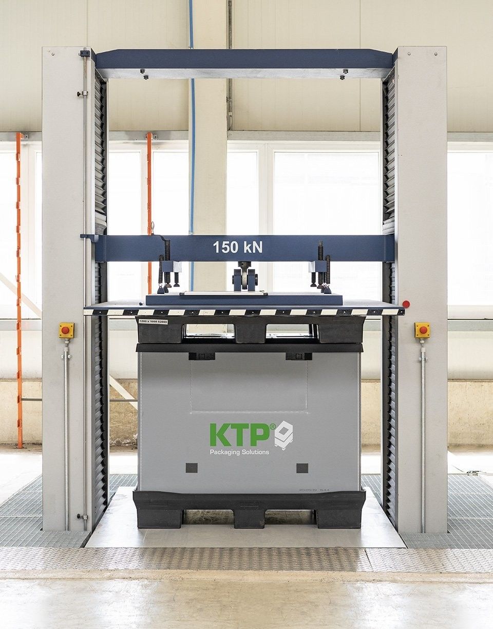 A testing machine with a force capacity of 150 kN, featuring a horizontal beam, clamps, and a base with the KTP Packaging Solutions logo, situated in a well-lit industrial environment.