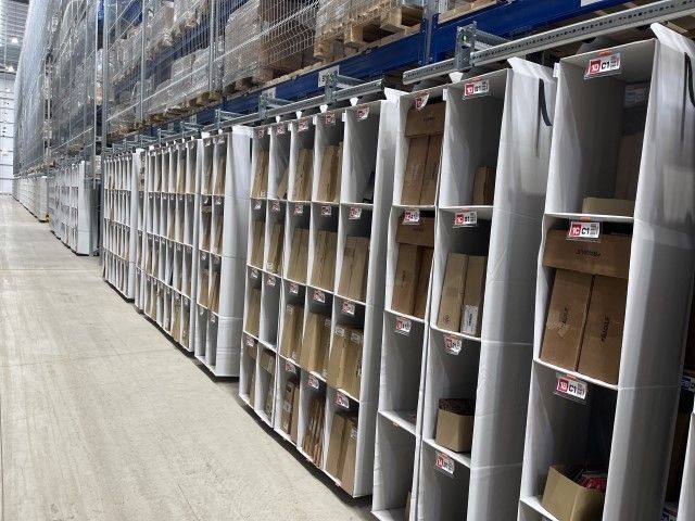 Rows of shelving units filled with cardboard boxes, set in a warehouse environment.