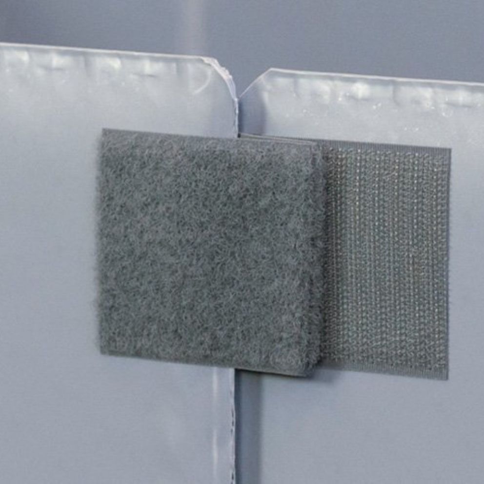 A close-up of two fabric velcro strips in gray, attached to a smooth gray surface.