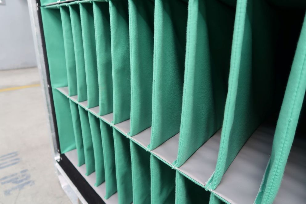 Close-up of a fabric storage organizer with multiple green compartments.