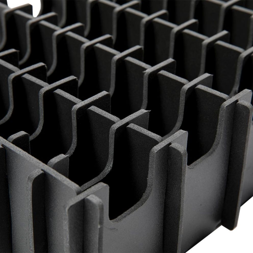 Close-up of a black foam organizer with multiple evenly spaced compartments, designed for holding various items securely.