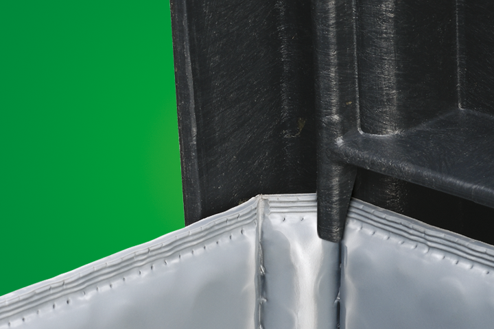 A close-up of a black corner section of a container, showing stitching on the gray fabric bottom. The background is a solid green color.