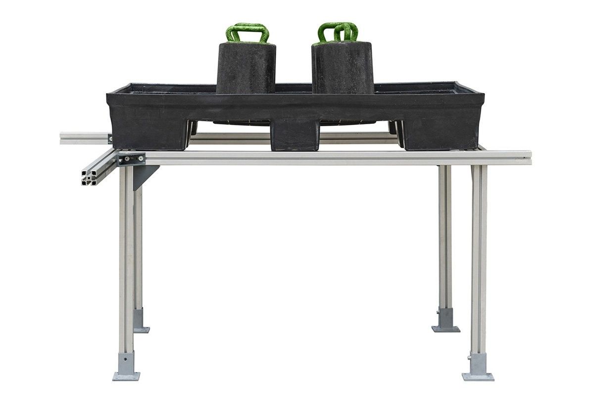 A black rectangular tray with two heavy weights sitting on a metal stand, designed for exercise or fitness activities.