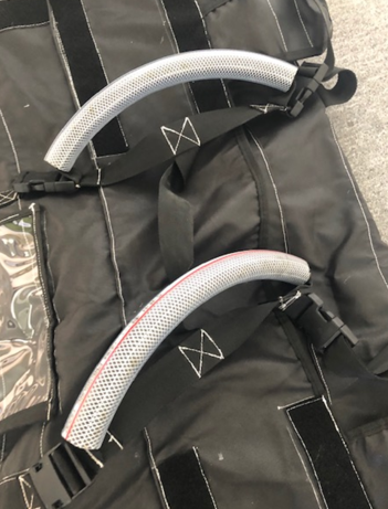 Two padded handles with mesh grips attached to a black bag with straps.