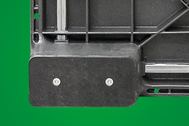 Black plastic object with screws, against a green background.