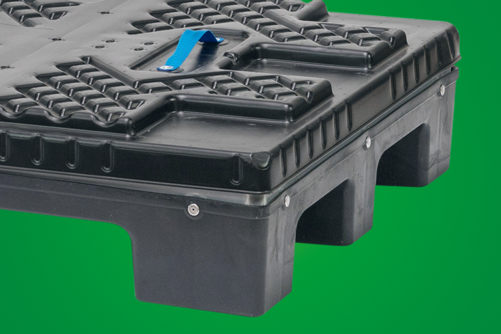 A close-up view of a black plastic pallet with a blue handle, set against a green background.