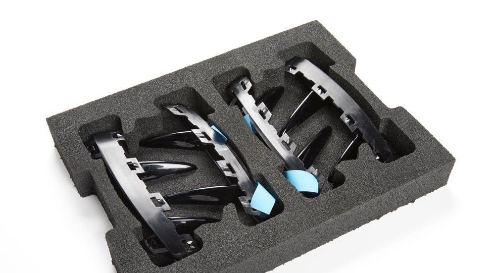 Black hair accessories with blue accents, placed in a protective foam insert.