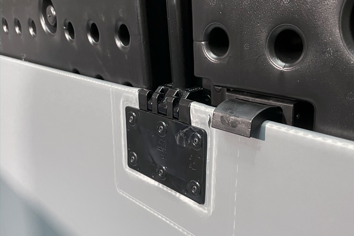 Close-up view of a mechanical hinge and locking mechanism on a modular structure, featuring a combination of black and white materials.