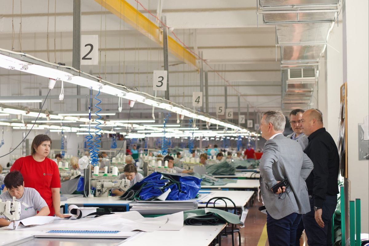 3 men inspecting two women who are nitting a specific textile