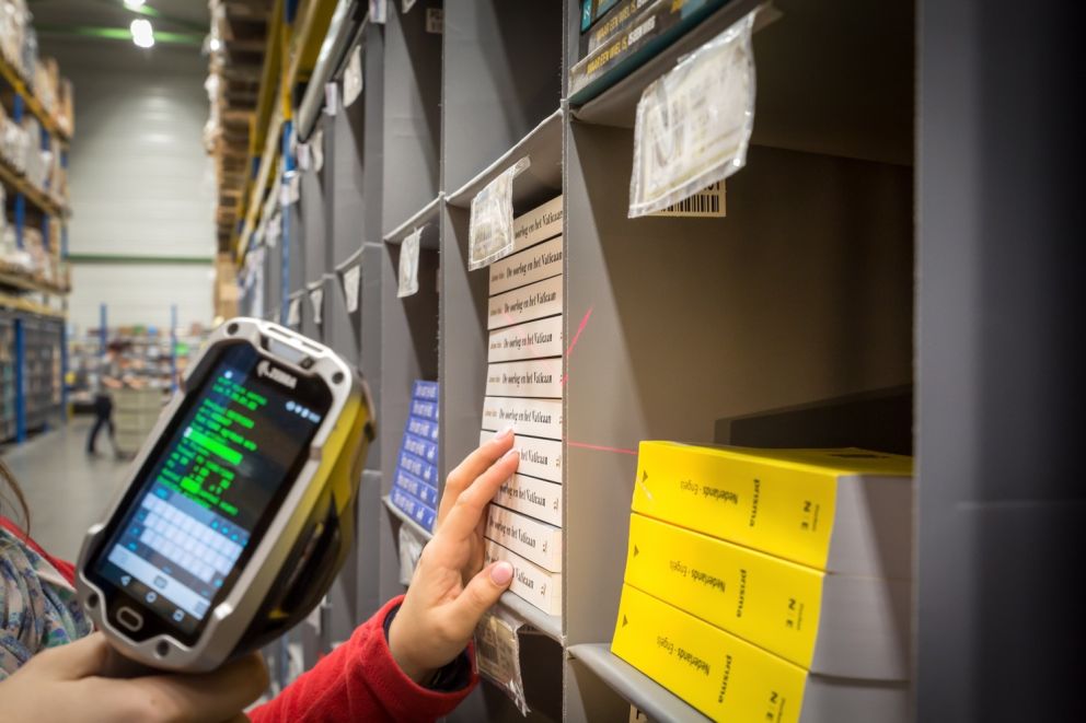 A person holding a scanner while picking books in a Storeganizer installation