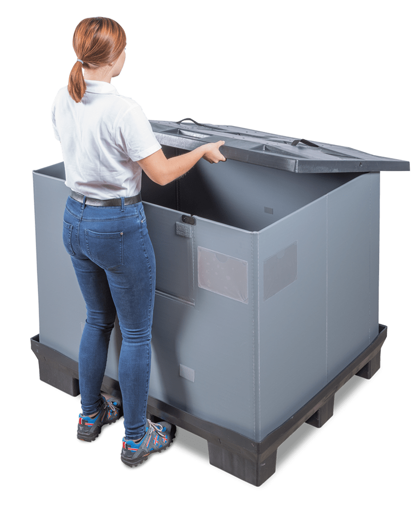 A person in a white shirt and blue jeans is standing next to a large gray container with a lid, preparing to open it.