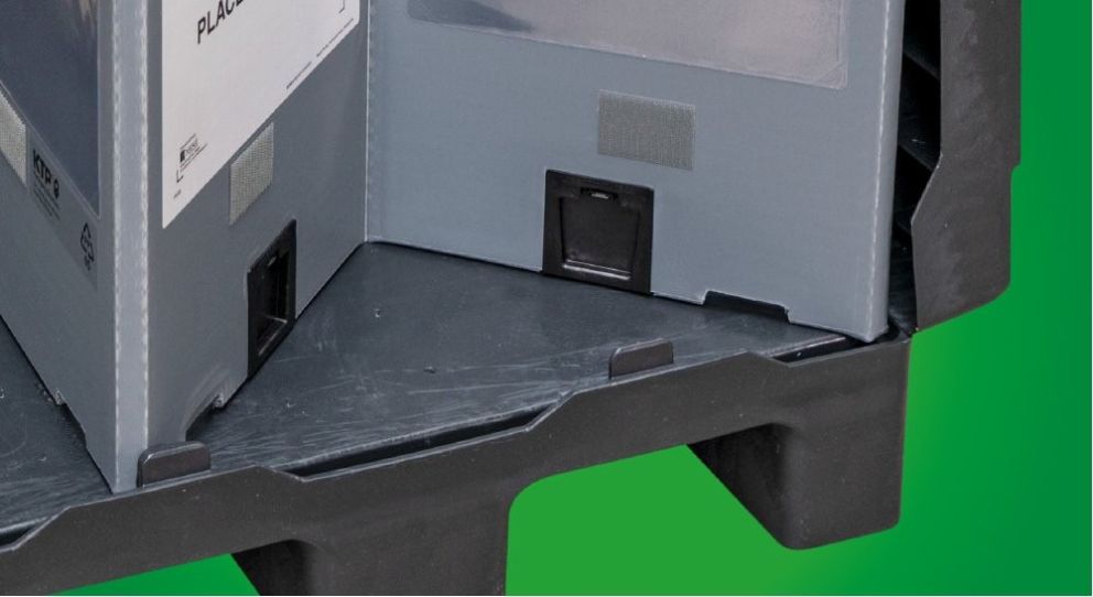 A close-up of two gray containers placed in a black plastic base, set against a green background.