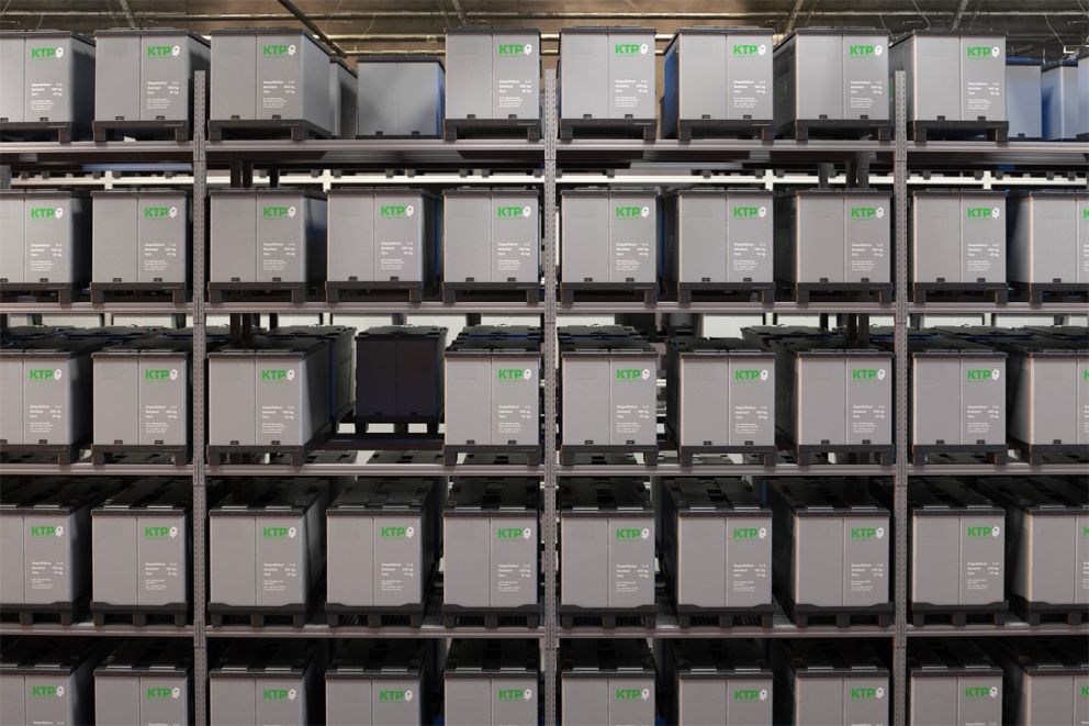 A storage area featuring multiple rows of gray storage containers labeled "KTP," stacked on industrial shelving.