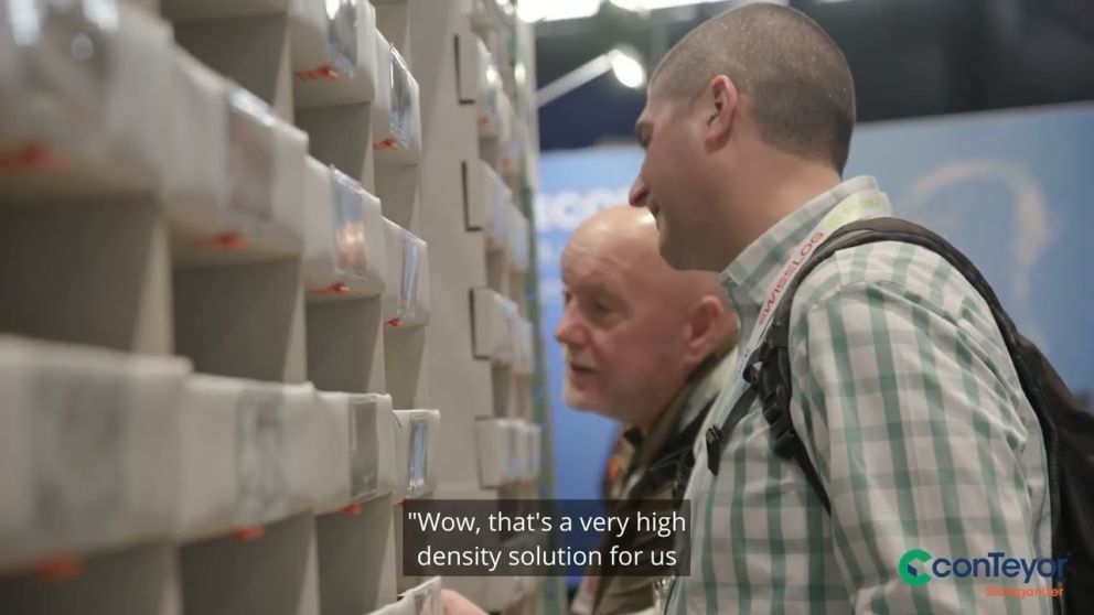 Two men are engaged in a discussion while examining a display of products or solutions at an exhibition.