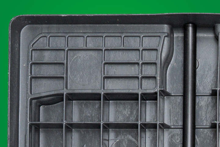 Close-up of a textured black storage tray with a grid pattern and cylindrical rod.
