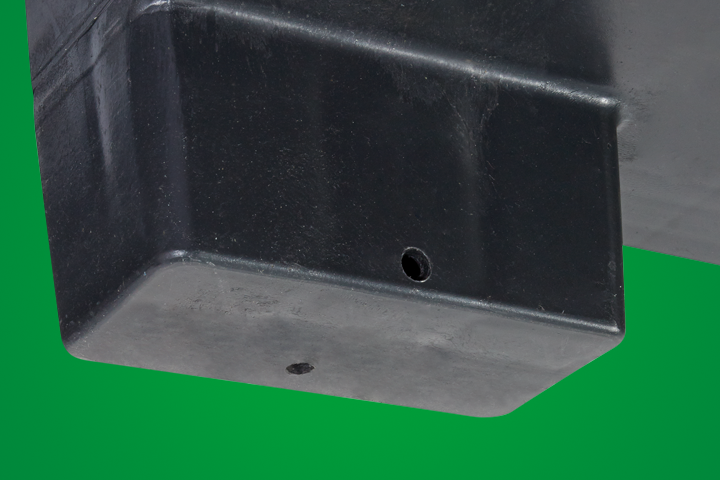 Close-up view of a black plastic component with two holes, set against a green background.