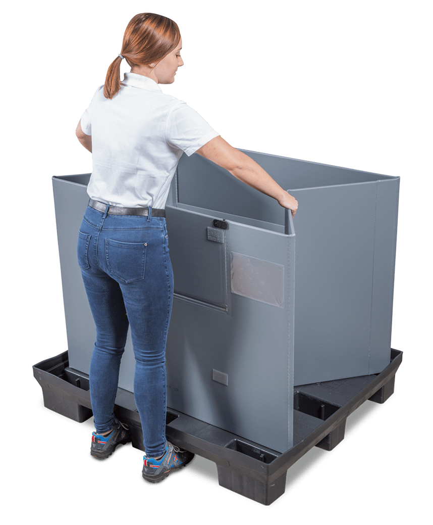 A woman in a white shirt and blue jeans is standing beside a large gray storage container, grasping its edge while preparing to interact with it.