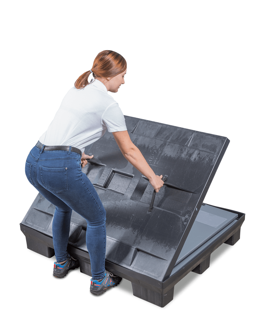 A person lifting a large black covering from a storage container, wearing a white shirt and blue jeans.