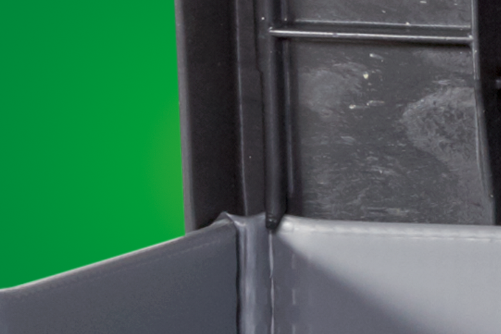 Close-up of a gray folder's inner edge against a green background, showing the binding and texture details.