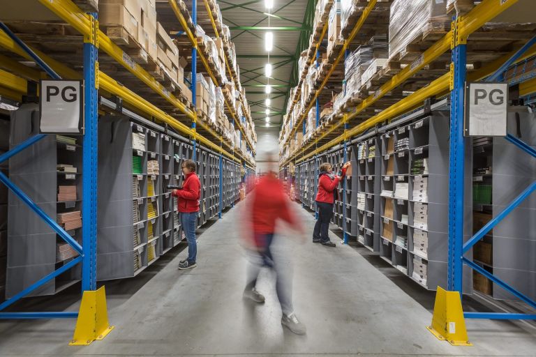 A warehouse with a couple of people walking in a Storeganizer setup