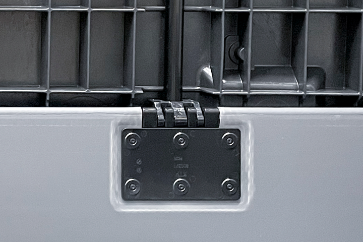 Black hinge attached to a metal panel with screws, part of a larger structure.