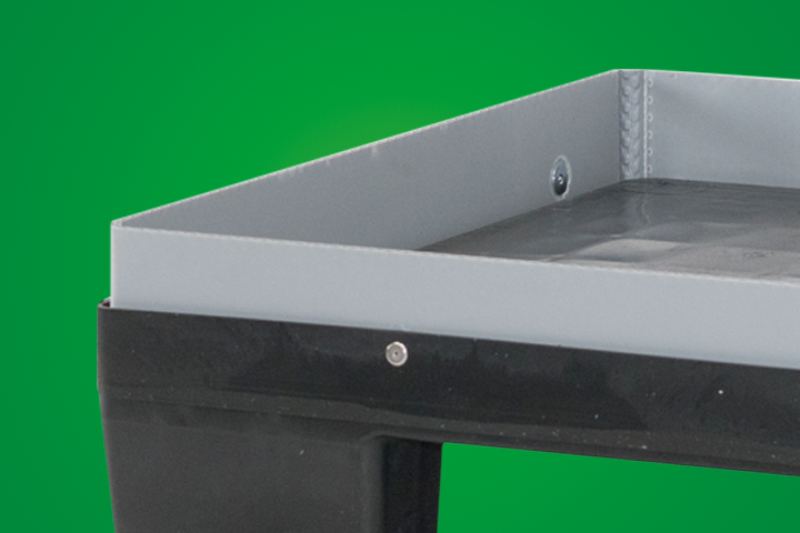 Close-up of a gray metal tray on a black base, with a green background.