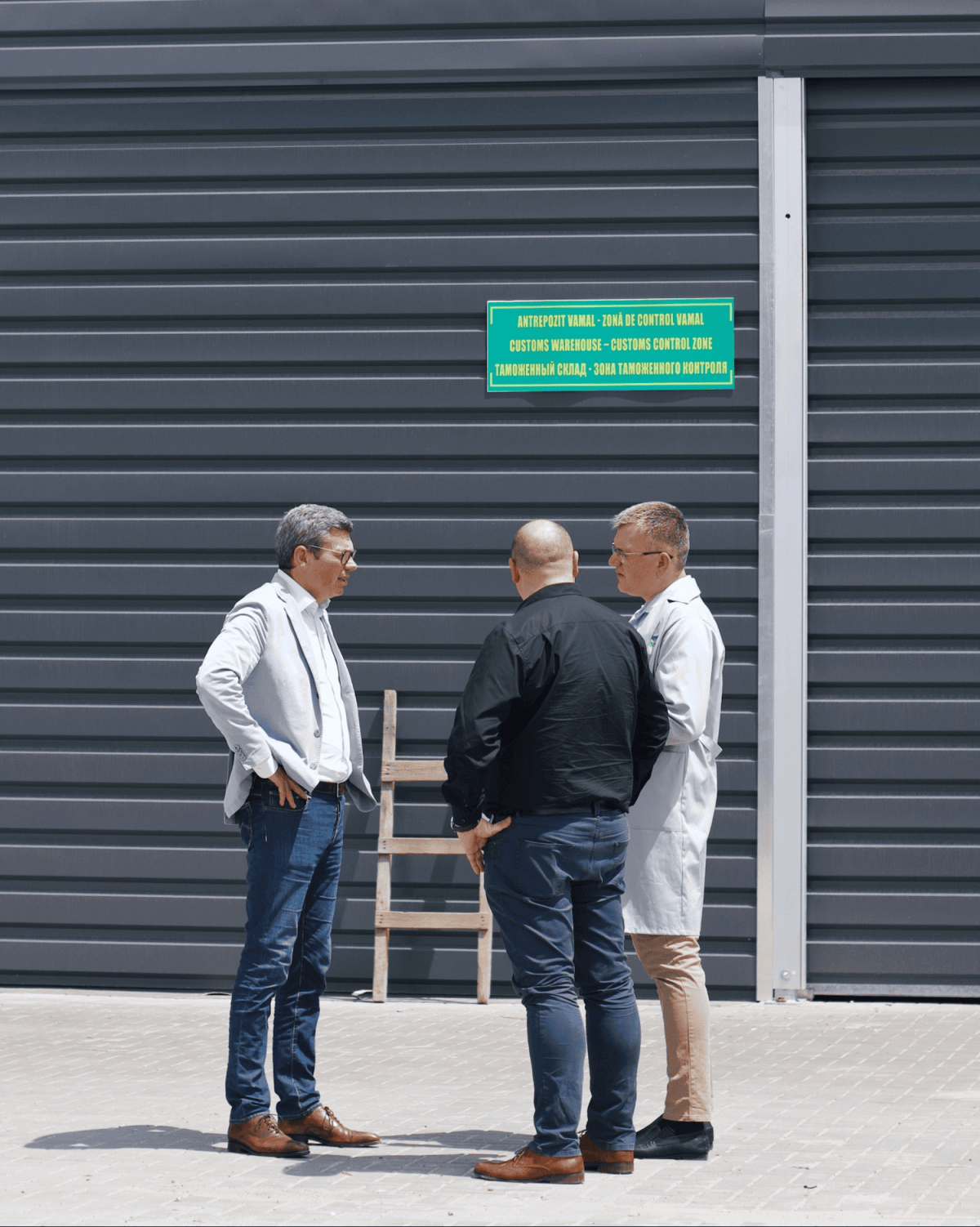 Three people talking to eachother against a background of a dark gray building