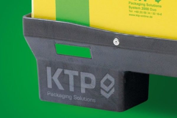 Close-up of a black plastic container with the text "KTP Packaging Solutions" and a logo, set against a green background.