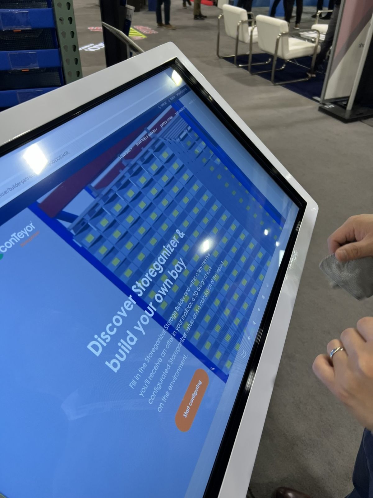 A person interacting with a touchscreen display featuring a storage configuration tool titled "Discover Storage and Build Your Own Bay." The screen shows a grid layout and a button to start configuring storage.