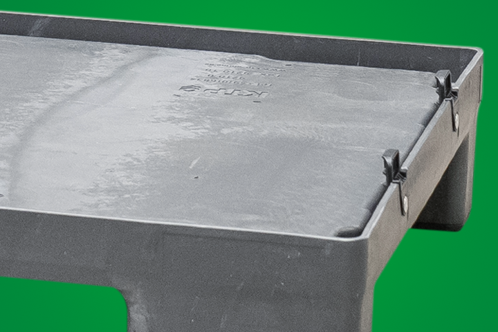 Black plastic tray with raised edges and clips, set against a green background.