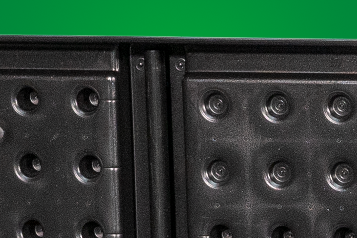 Close-up of a textured black surface featuring circular indentations, with a slight hinge visible on the left side.