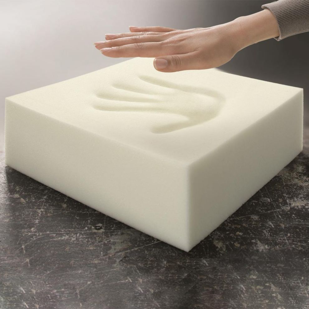 A hand pressing down on a soft, white foam block, leaving an imprint of a hand.