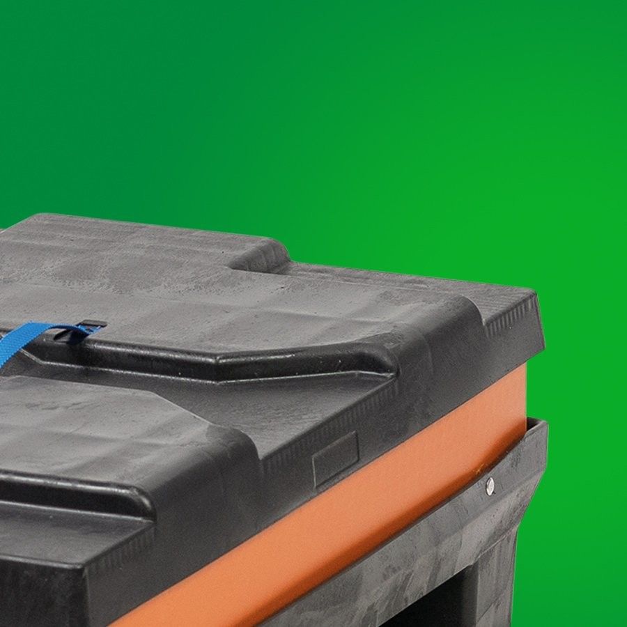 A close-up of a black plastic storage container with an orange accent, secured with a blue strap, against a green background.